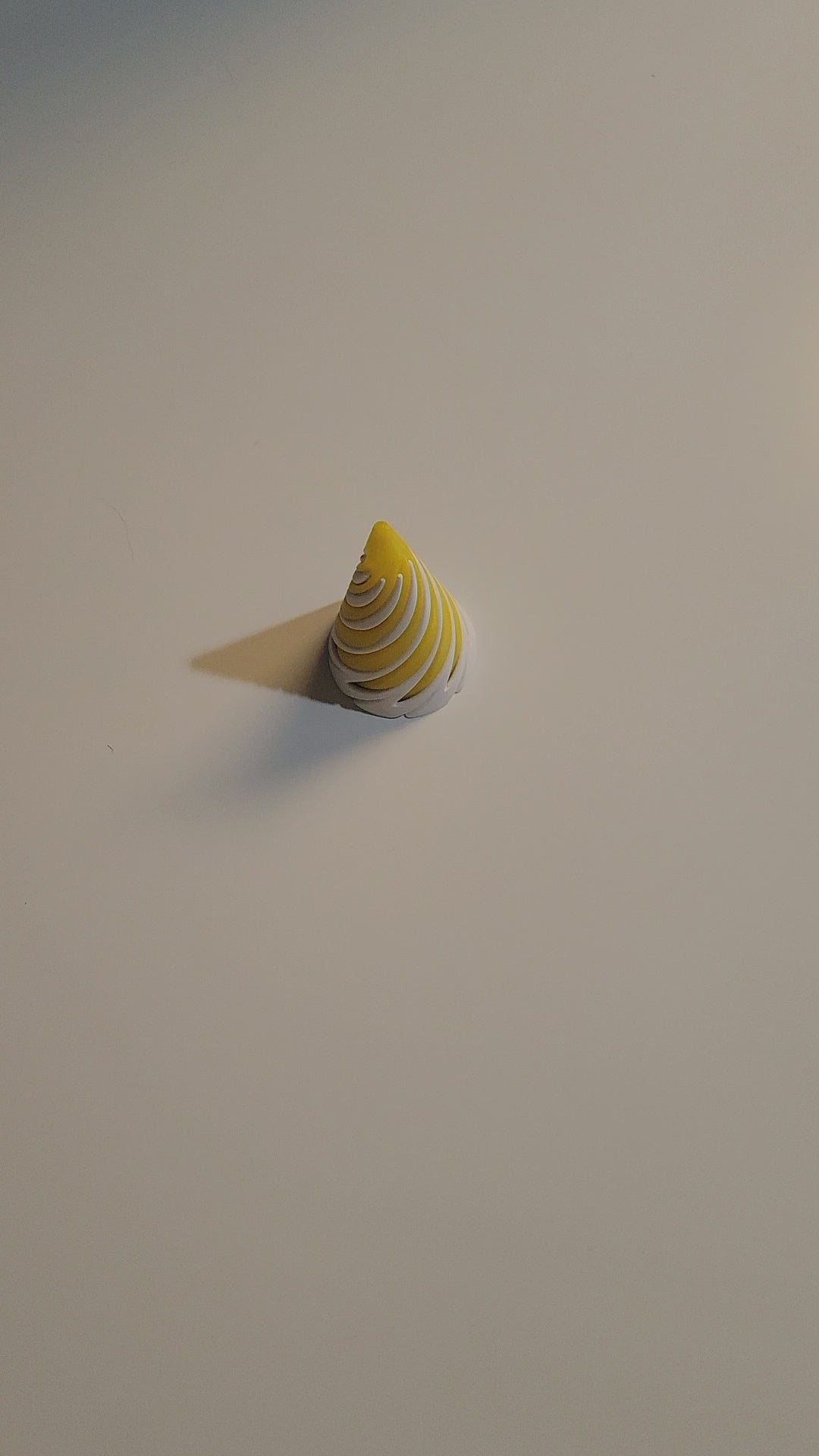 Solar Yellow and Arctic White spiralized cone fidget with hands displaying twisting movement while 2 pieces pass through each other in all ways on light grey backdrop. 