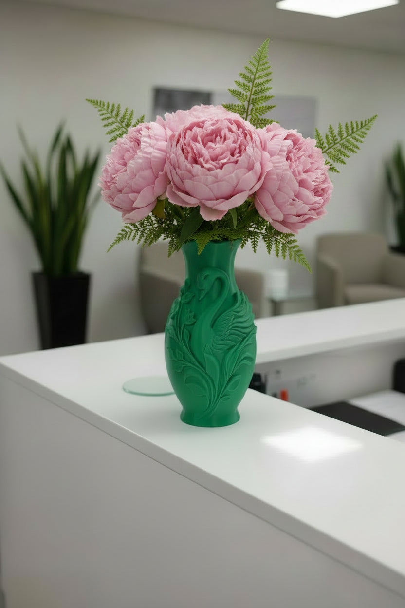 Emerald Green 3D-printed swan vase with sculptured vines and leaves holding pink peonies and ferns on a reception desk.