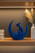 Cobalt Blue 3D-printed sculpture of a serene woman in a gown sitting on a crescent moon styled on a shelf.