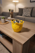 Solar Yellow 3D-printed tulip bowl filled with decorative river rocks on a coffee table in a modern living room.