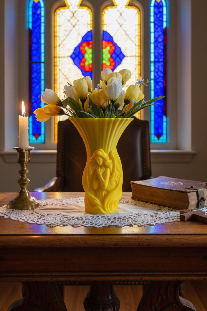 Solar Yellow 3D-printed self-embracing angel vase with a flared top holding yellow and white tulips on a desk by a bible.