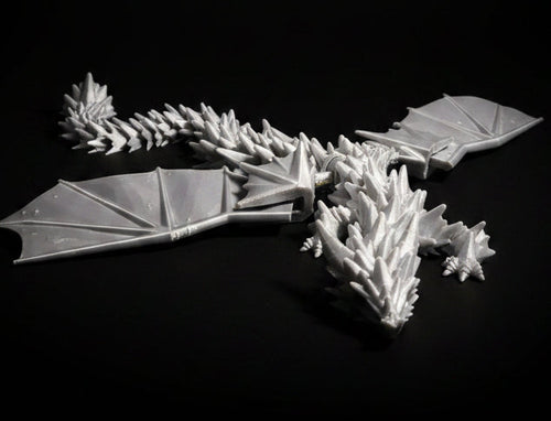 Silver Silk 3D-printed articulated dragon desktop fidget with bat style wings and a spiked back on a black background.