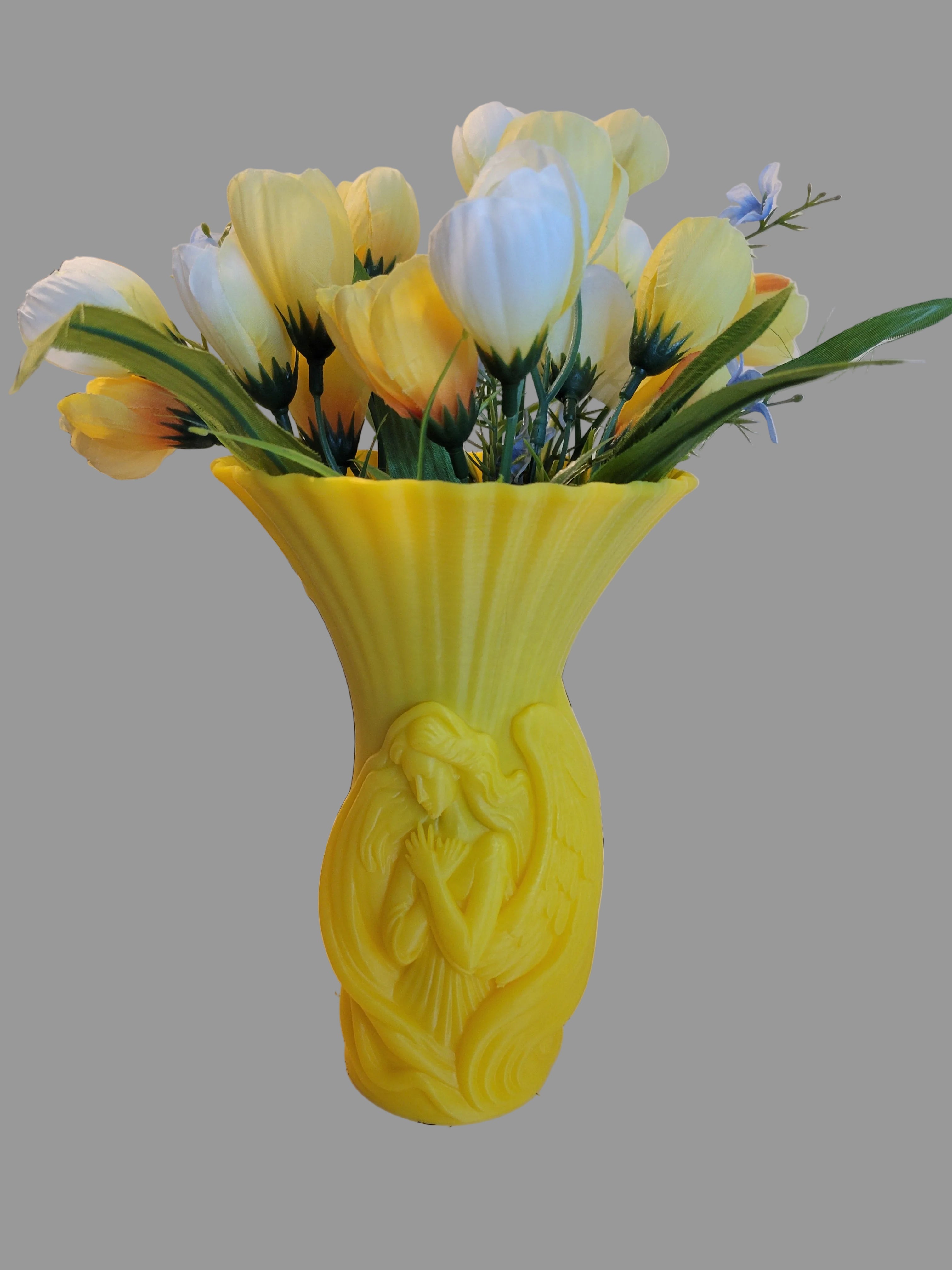 Solar Yellow 3D-printed embracing angel vase with flared top holding yellow and white tulips on a gray background.