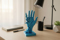 Translucent Blue 3D-printed pixelated hand sculpture on a desktop with modern office accessories.