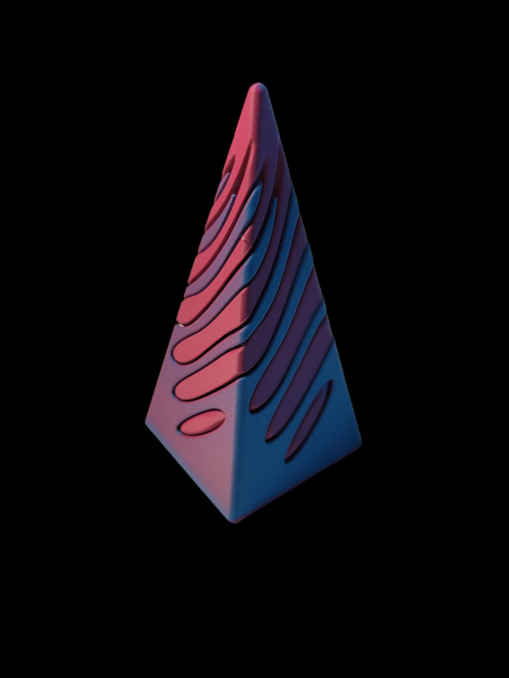 Teal to Pink color-shifting 3D-printed pyramid passthrough fidget showing carved spiral grooves in its solid form on a black background.