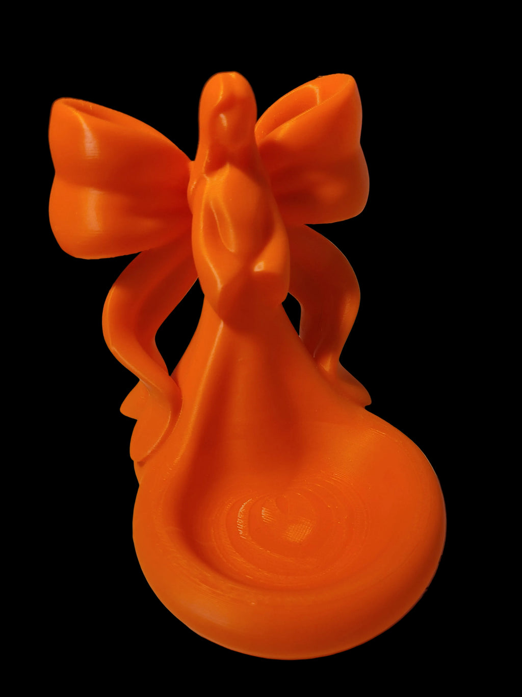 Sunset Orange 3D-printed tea light holder featuring an angelic figurine with a large streaming bow for wings set against a black background.