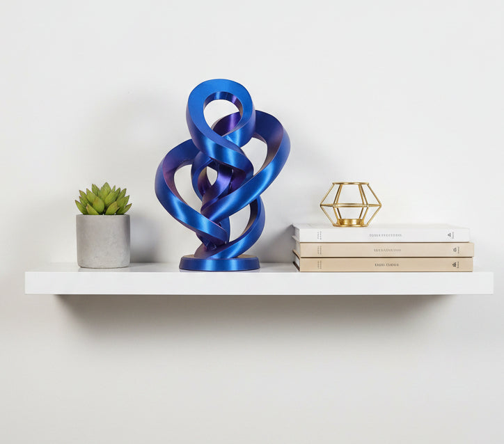 Blue to Purple Silk color-shifting 3D-printed curvy infinity sculpture on a white shelf next to a small succulent plant.