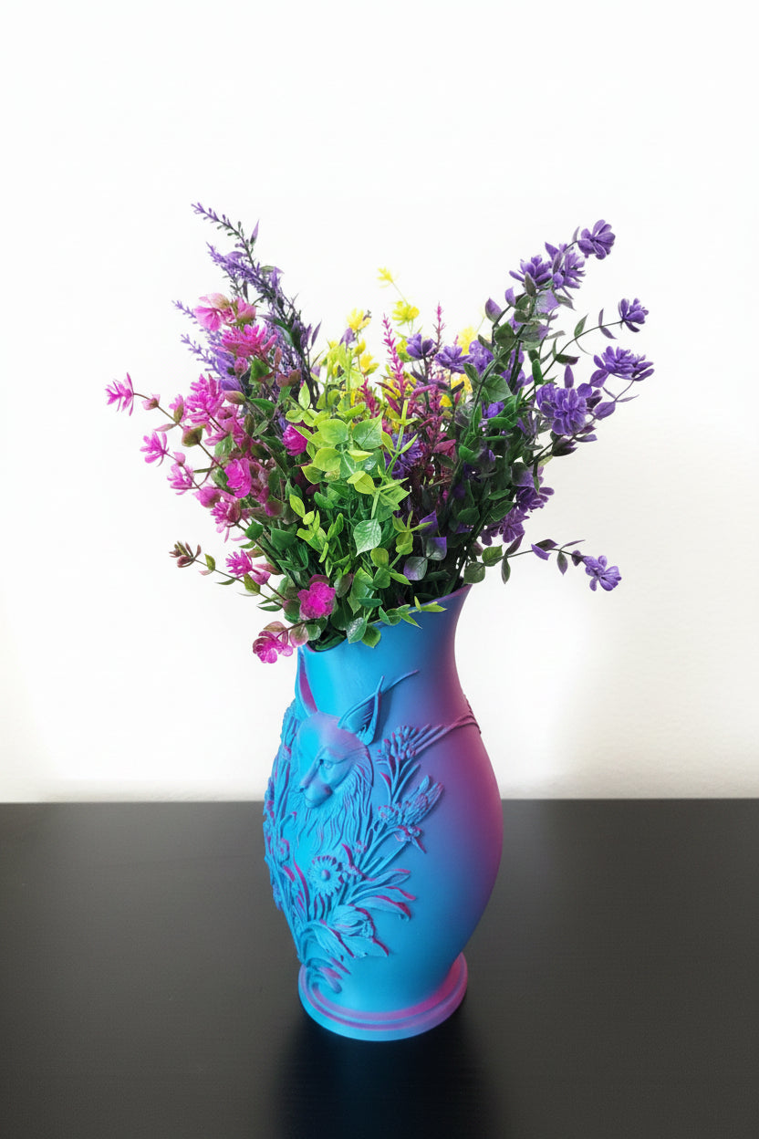 Teal to Pink color-shifting 3D-printed vase with embossed floral and cat design holding colorful wildflowers on black table.